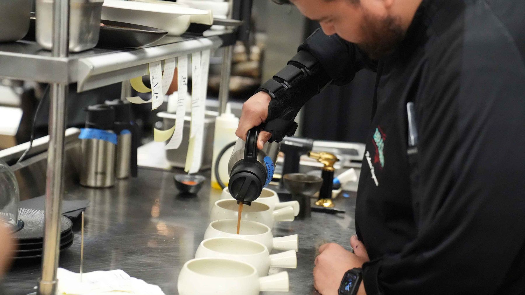 Chef Roberto Higuera pouring broth into bowls at the pass